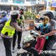 Petugas membagikan snack kepada anak-anak yang mengenakan helm